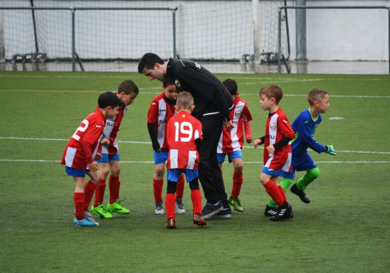 Trainer bespricht sich mit Kindern auf dem Fußballplatz